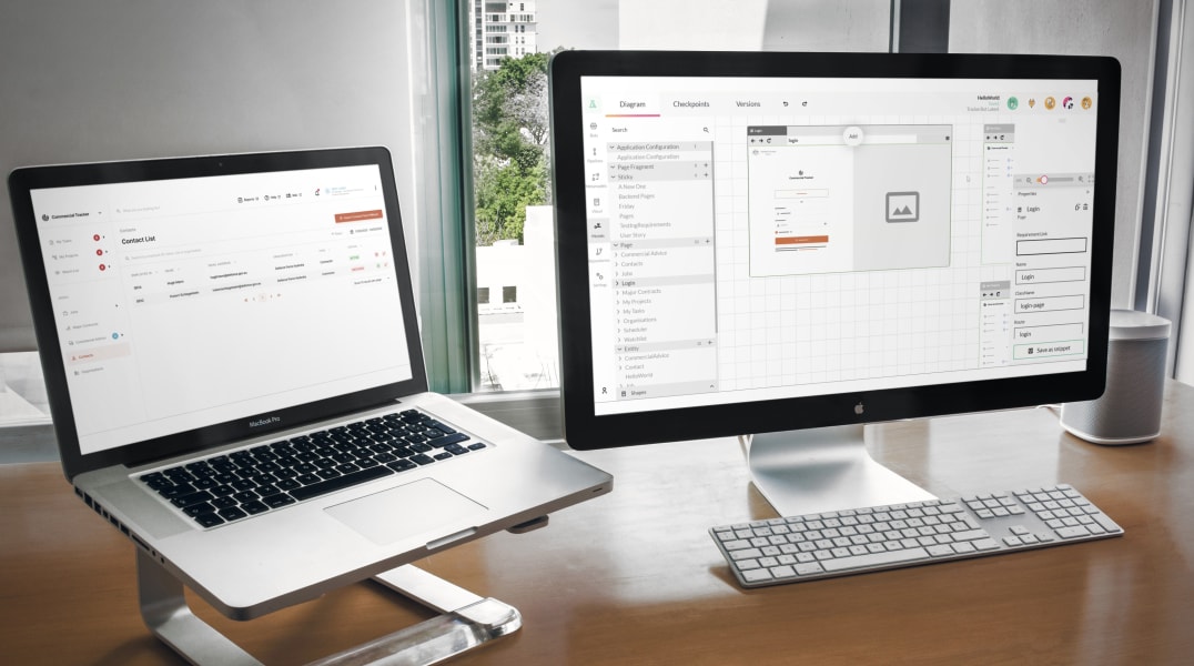 A photo of two computer screens with the new tracker interface showing
