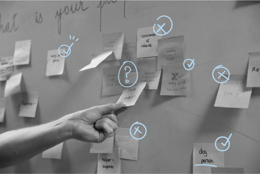 A hand pulling off a post it note on the wall. he wall is covered in post-it-notes 