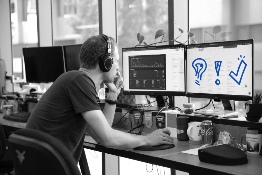 A workingmouse employees wearing headphones is looking at a computer screen