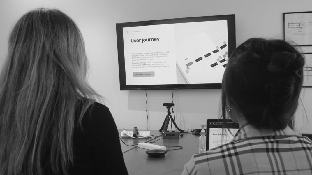 Two people are looking at a screen that says: User Journey