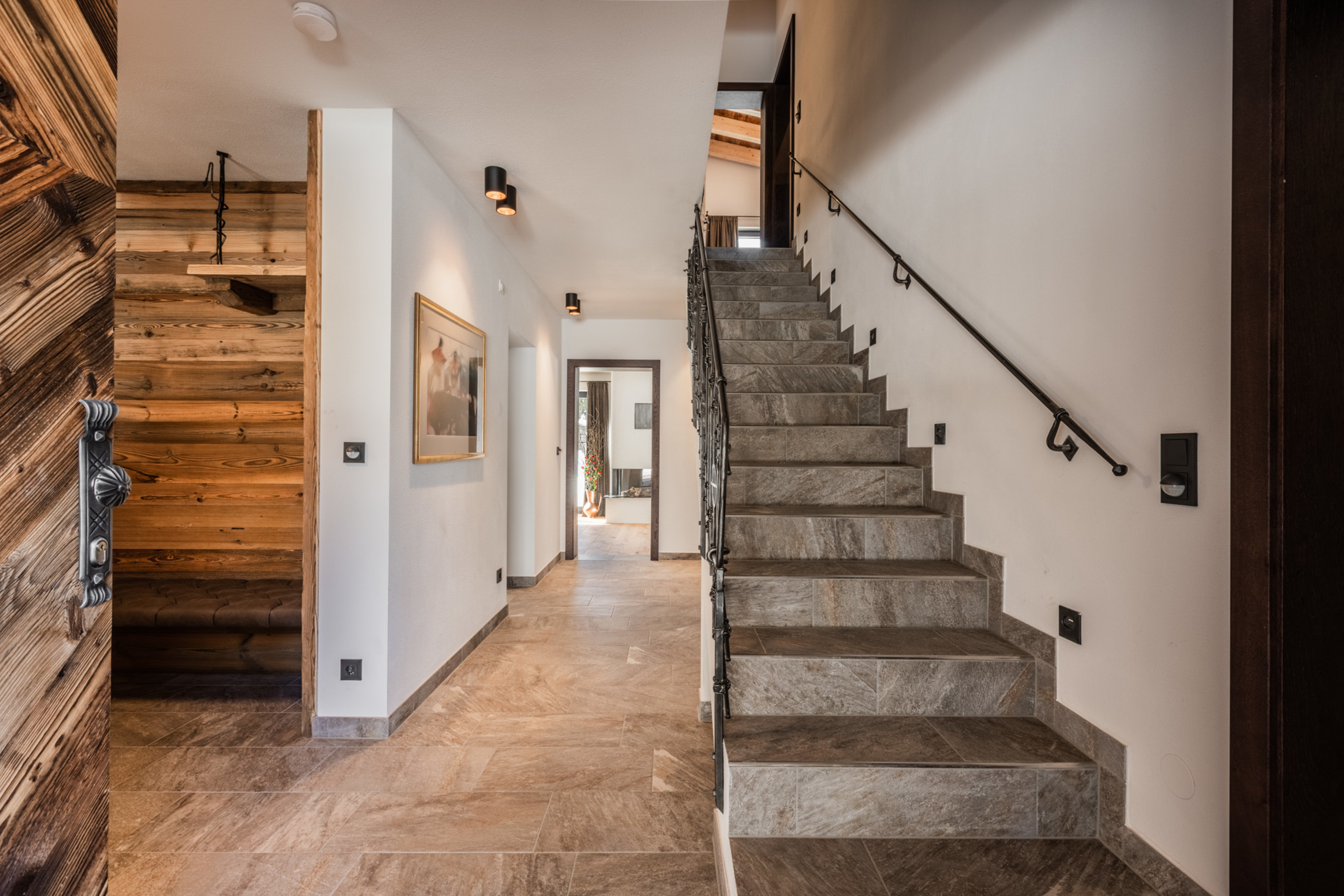 Großzügiges Vorzimmer mit Holzdetails, Sitzbank und Treppe - zentraler Eingangsbereich des Chalets