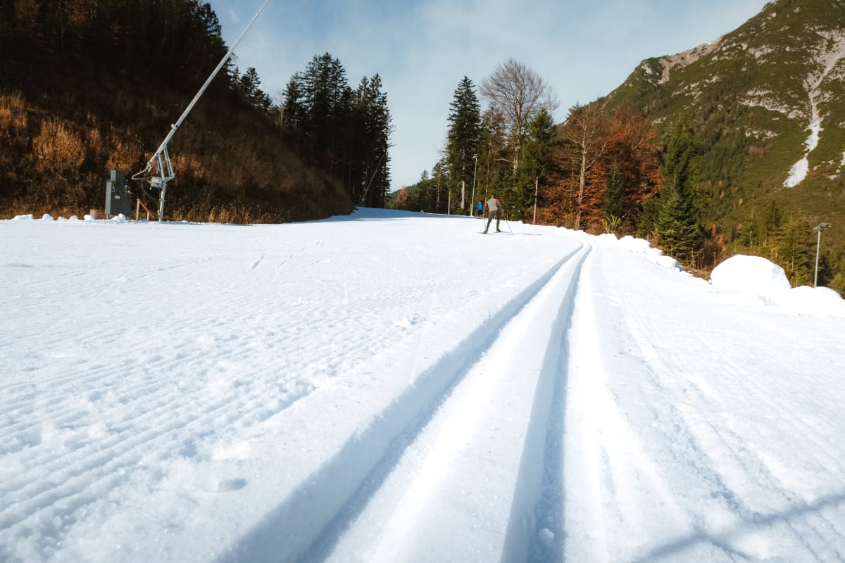 Čerstvě upravená snowfarmingová stopa v Leutaschi na začátku zimy, na okraji podzimní stromy