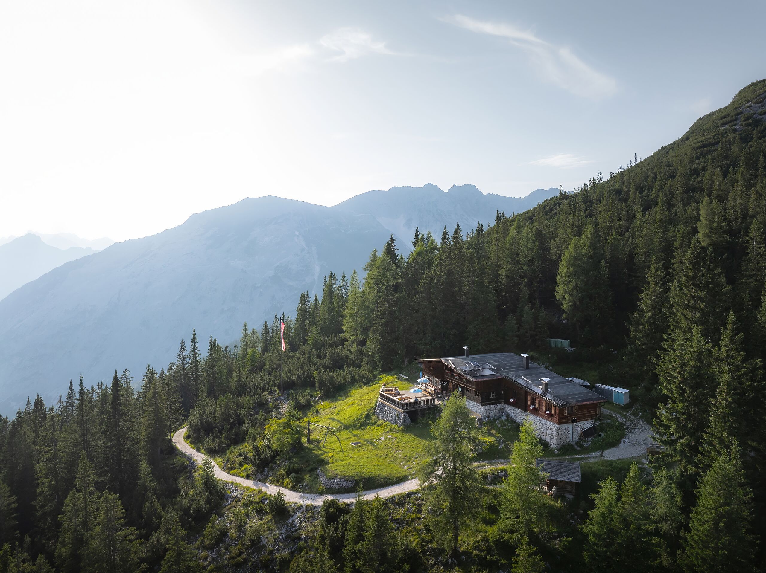 Snímek Pleisenhütte z dronu s nízko stojícím sluncem – panorama vrcholů Karwendelu