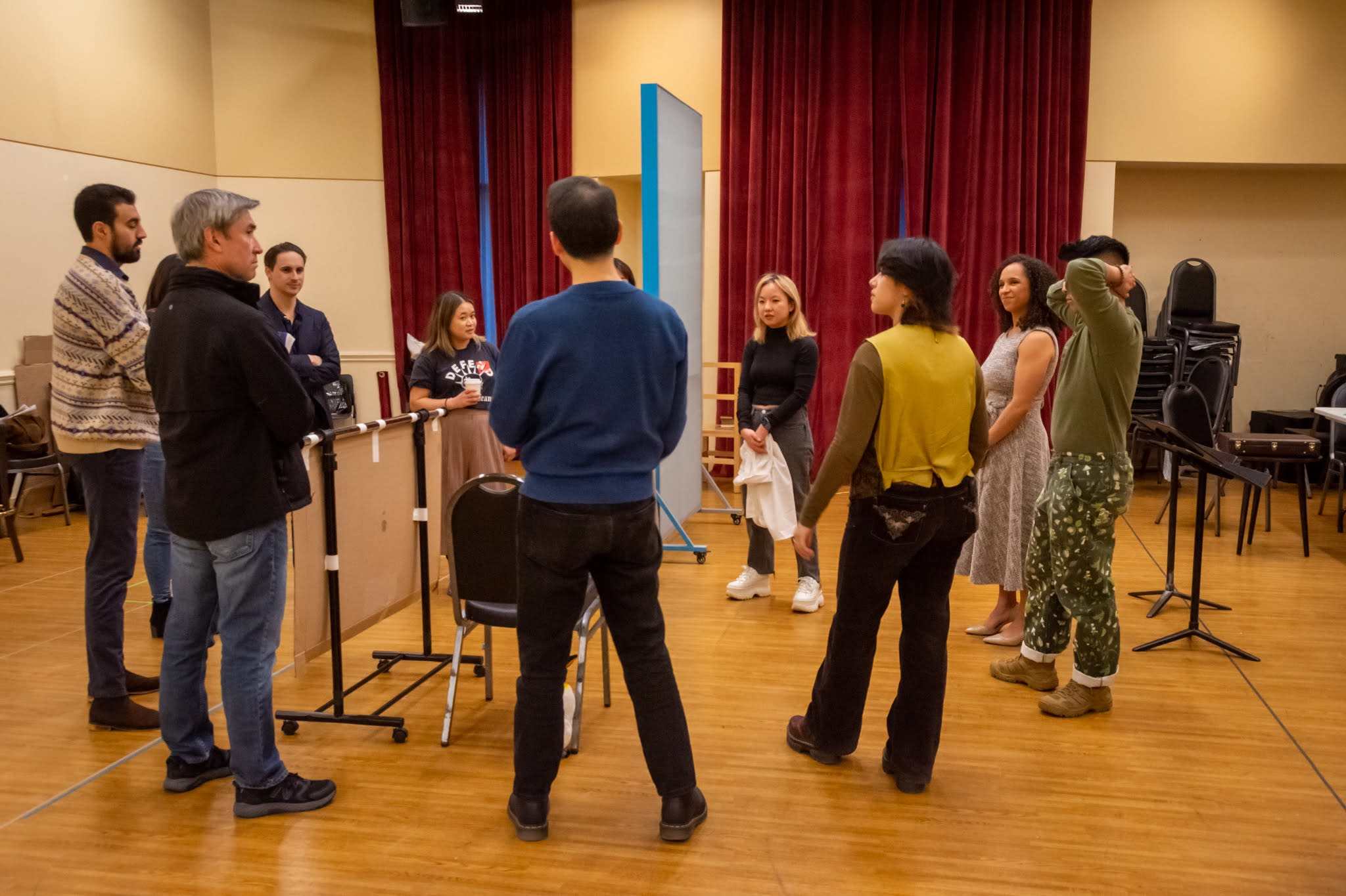 A working rehearsal: the full company standing in a circle in the rehearsal hall