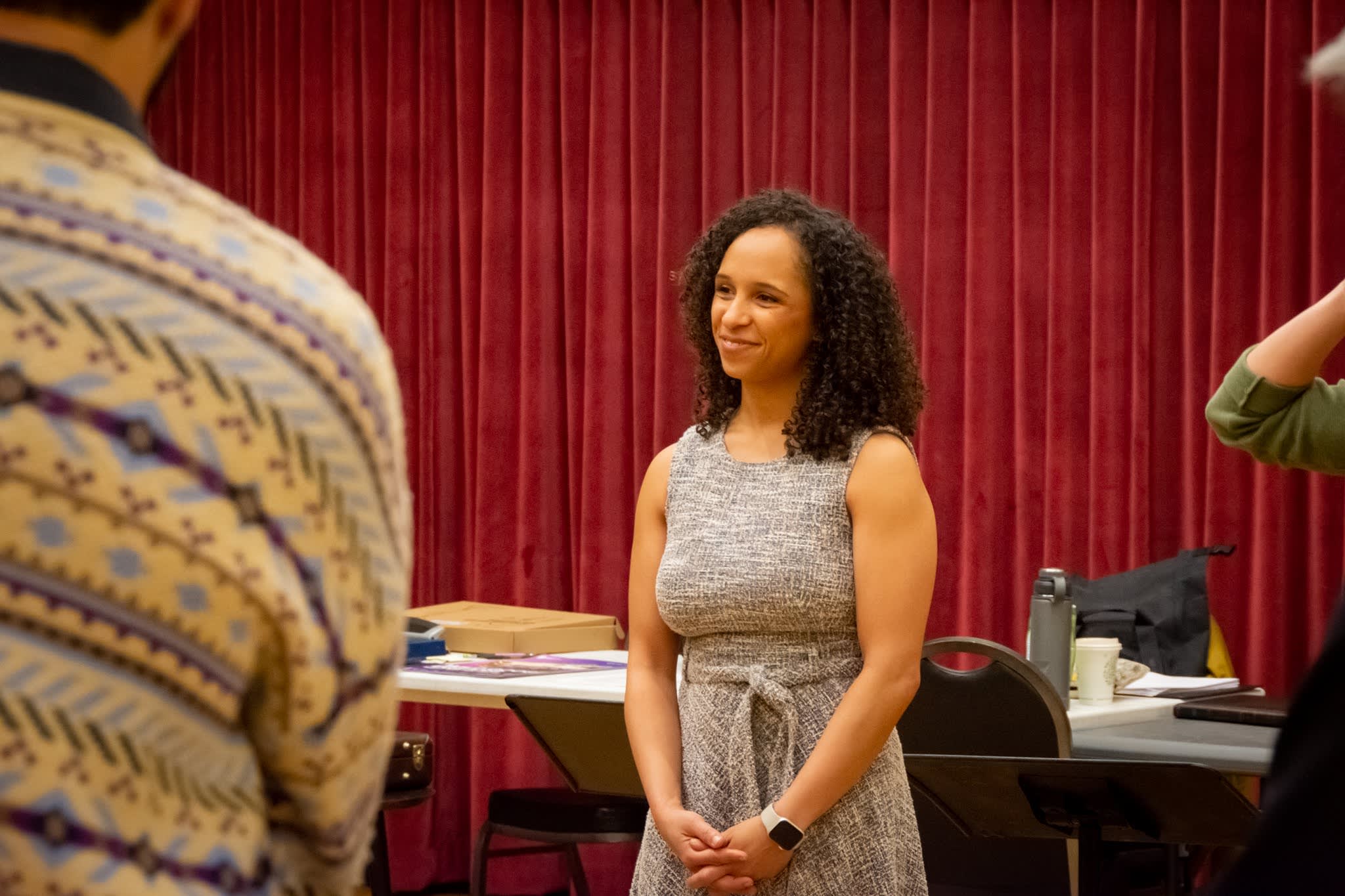 Kira Troilo in a rehearsal room, smiling warmly while listening during a working session