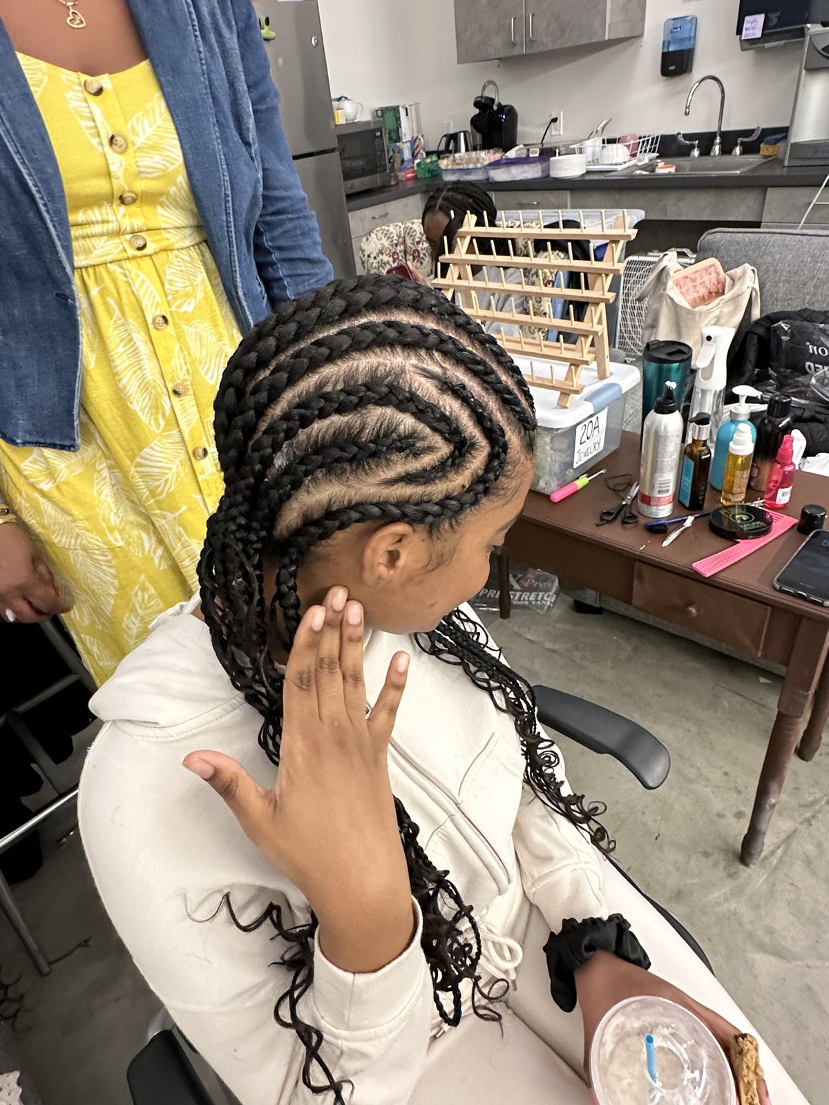 A performer's freshly installed feed-in braids on Texture Ready Salon Day, styling station behind her