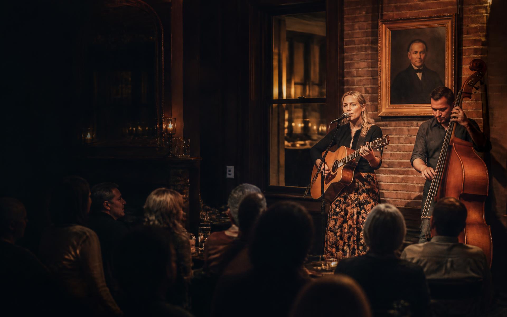 Singer with an acoustic guitar and an upright bass player performing live music at Rumsey Tavern in Shepherdstown