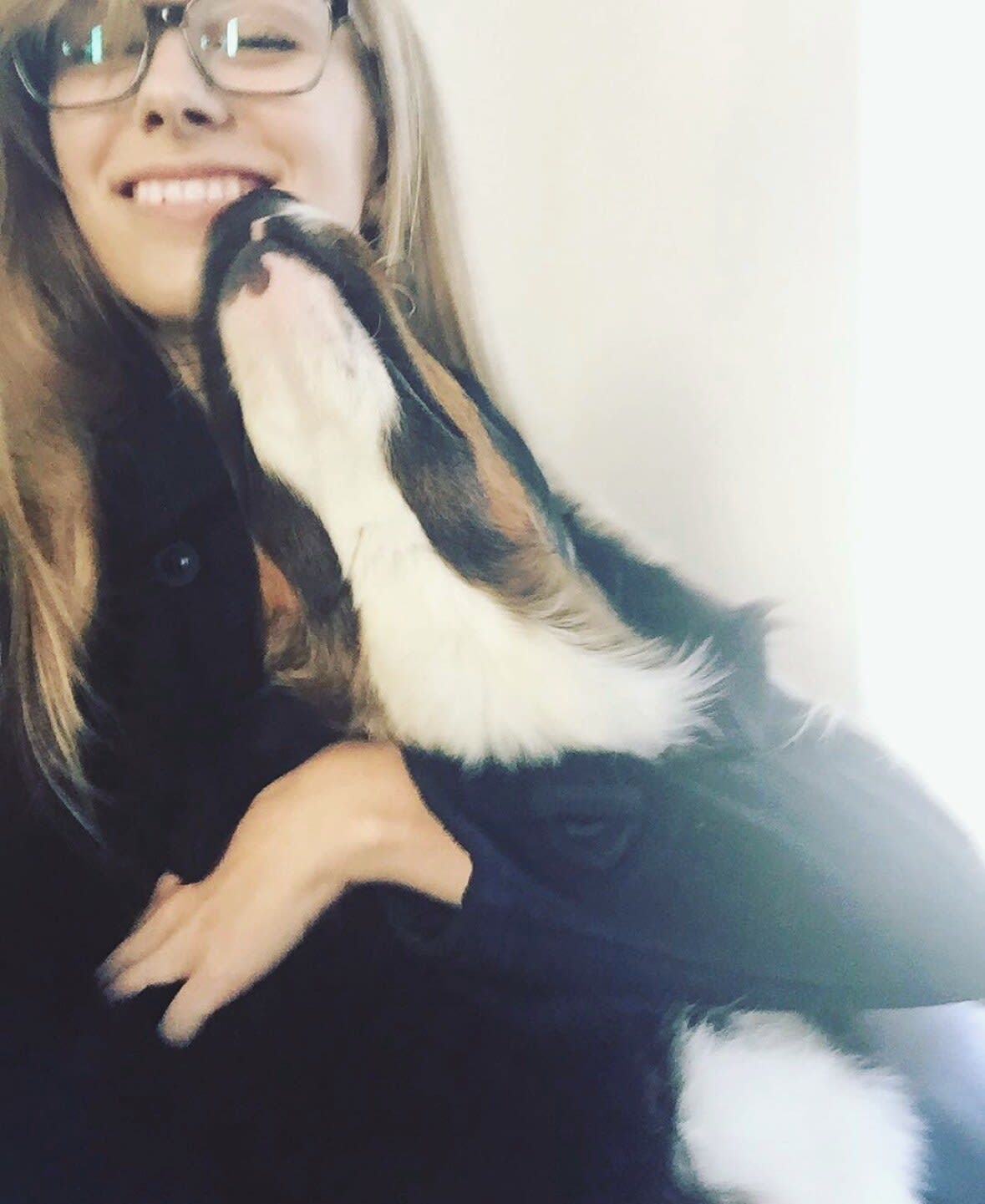 Charlie laughing as a Bernese mountain dog puppy licks her face