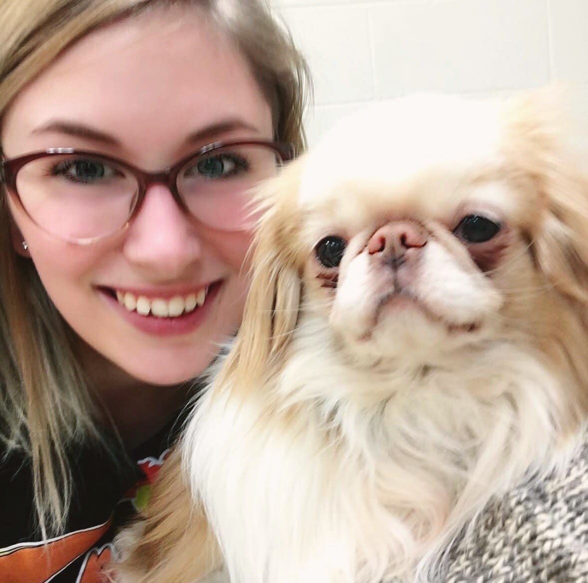 Charlie smiling beside a fluffy cream and white Japanese chin