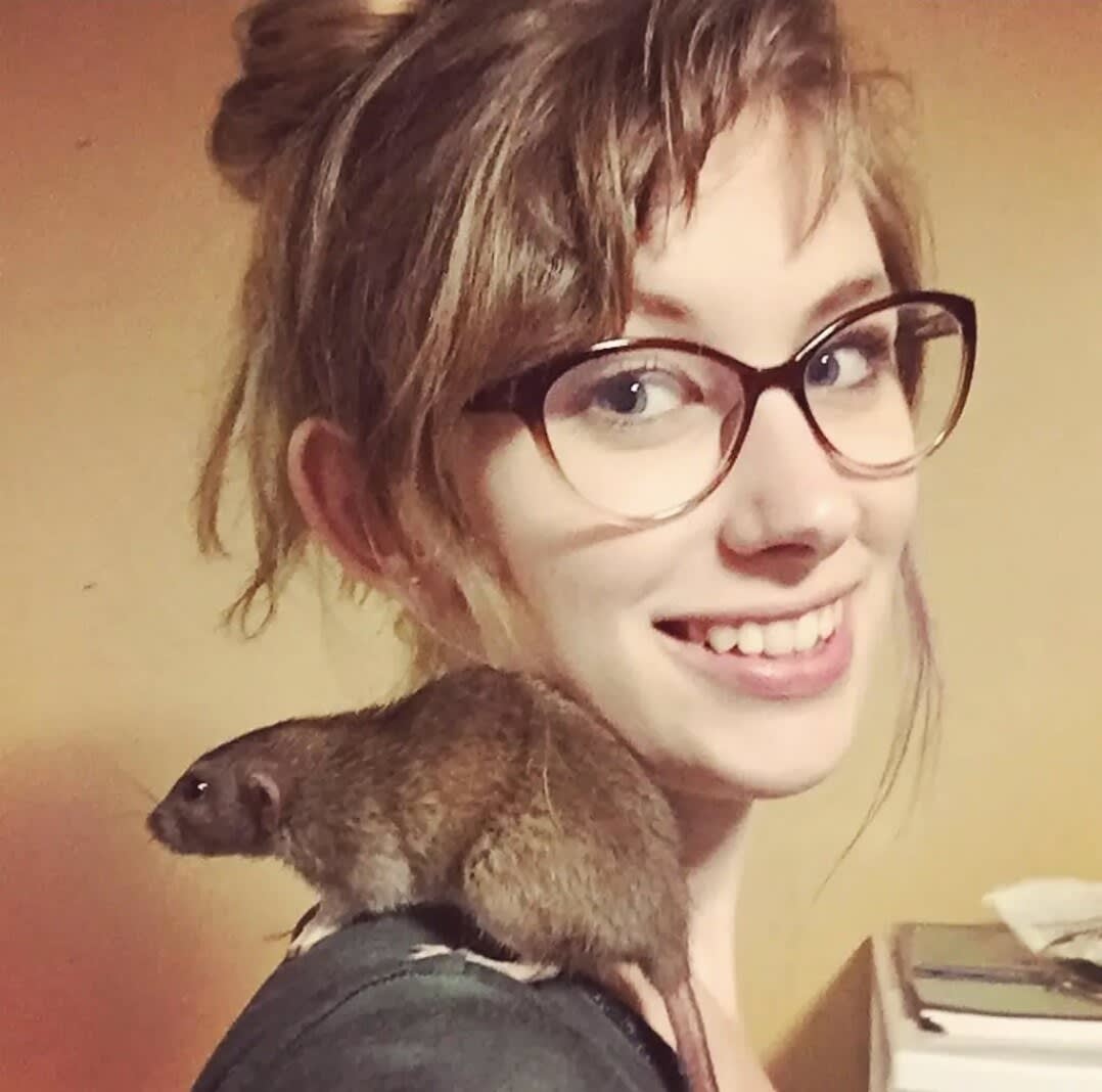Charlie smiling with a brown pet rat sitting on her shoulder