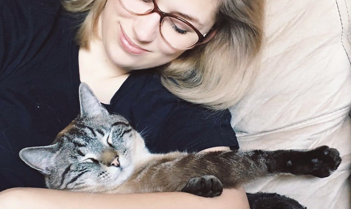 Charlie lying down with a sleepy lynx-point tabby cat stretched across her chest