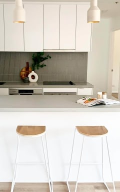 CBD Melbourne kitchen renovation. Off white kitchen with two wooden stools and hanging lights