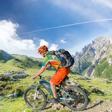 Man wearing biking protective equipment’s on a mountain bike biking on a trail through mountains