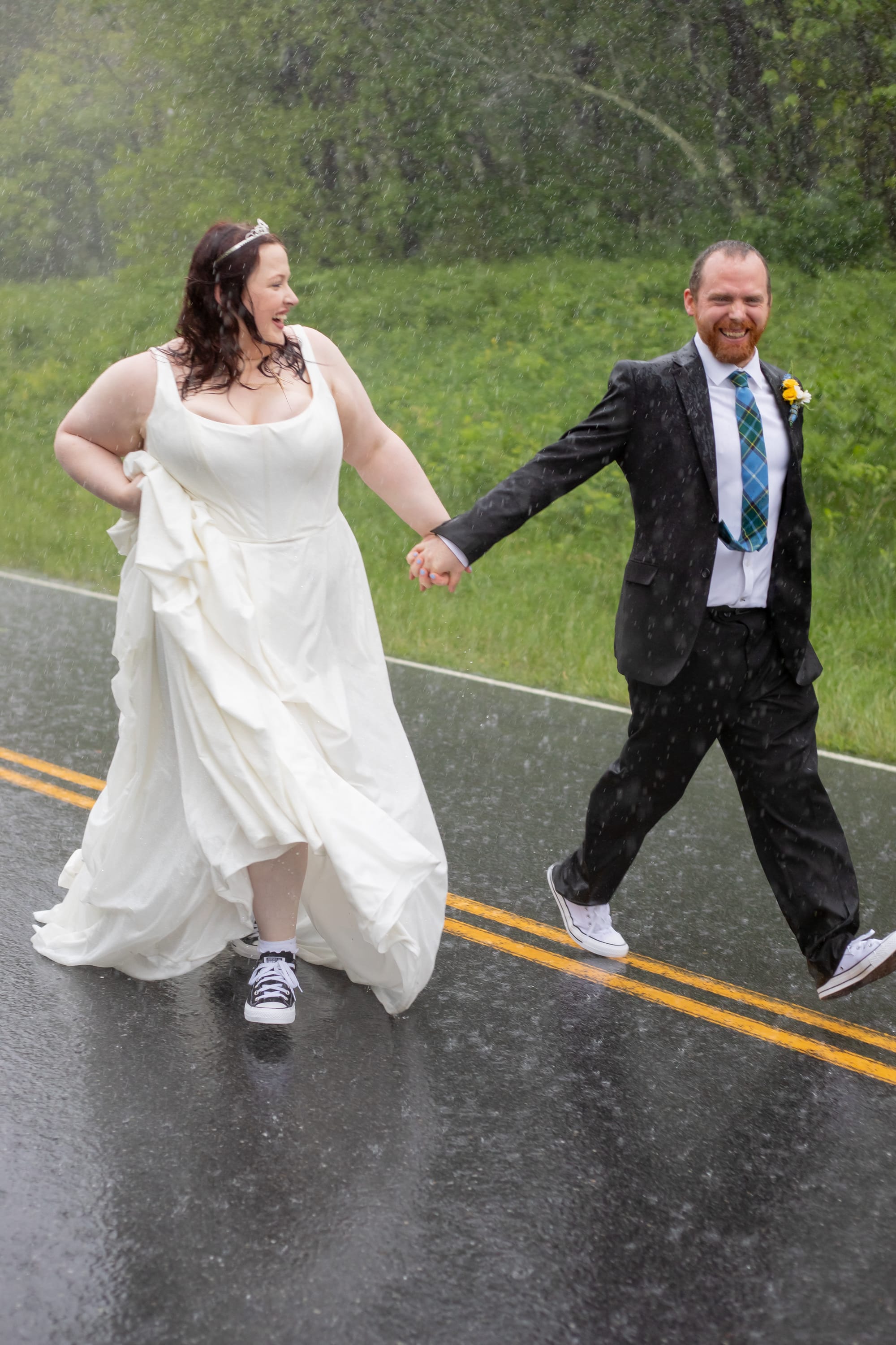 Couple laughing and walking hand in hand in the pouring rain on Skyline Drive in Converse sneakers, Shenandoah National Park