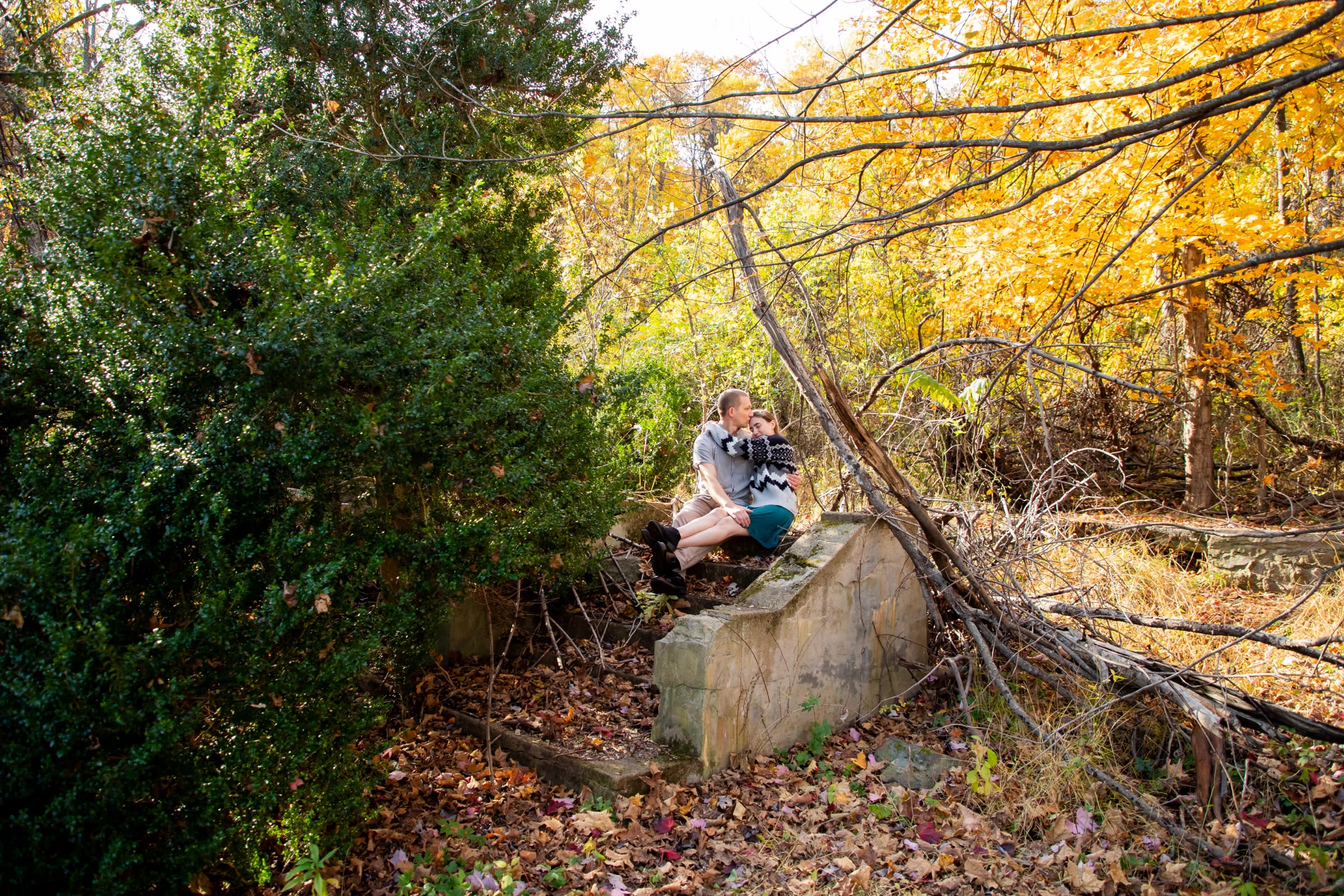 Couple kissing among the ruins at Snead Farm, surrounded by golden fall foliage in Shenandoah National Park