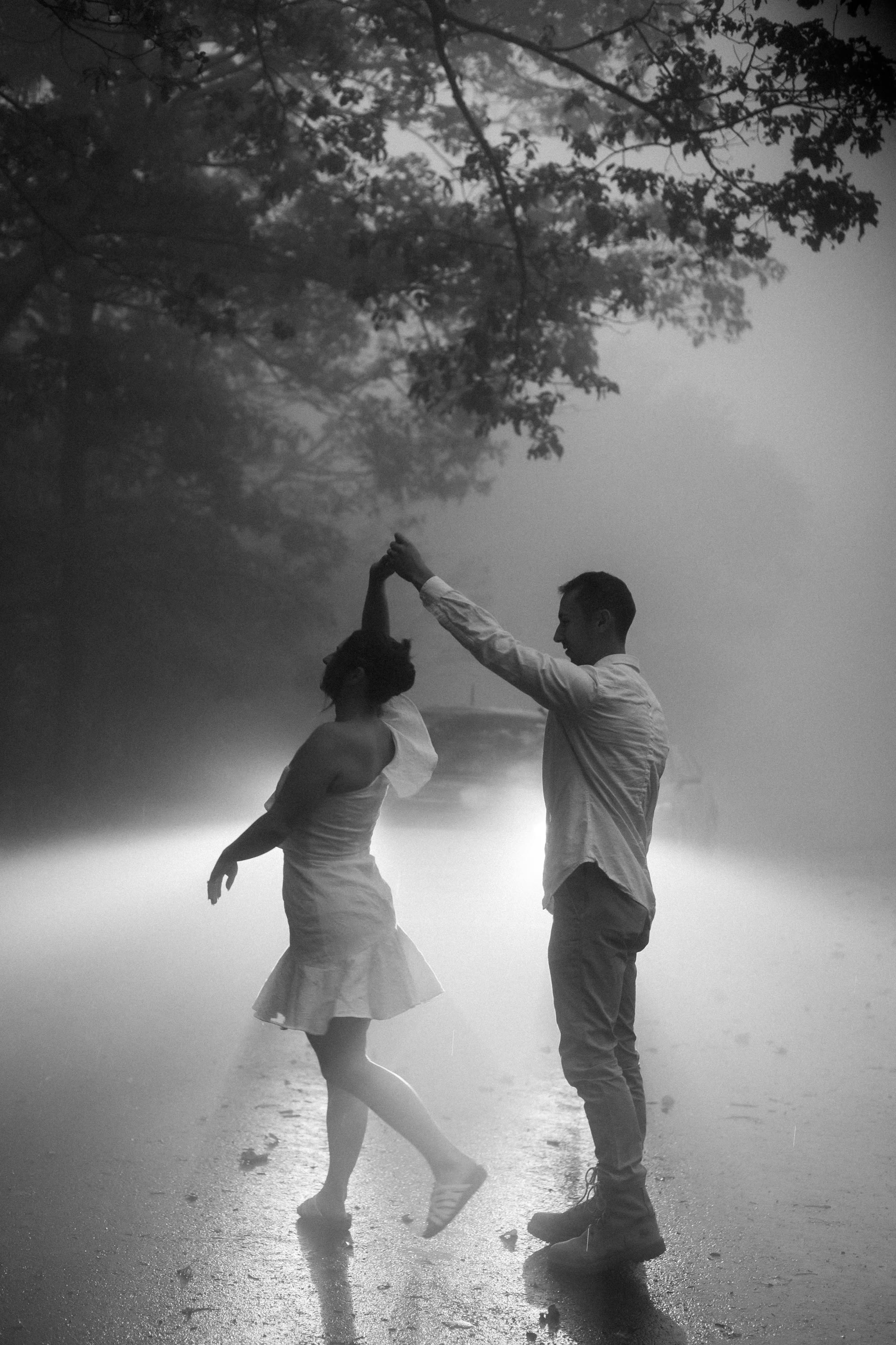 Couple dancing together on a foggy Skyline Drive road in the rain, black and white photograph, Shenandoah National Park