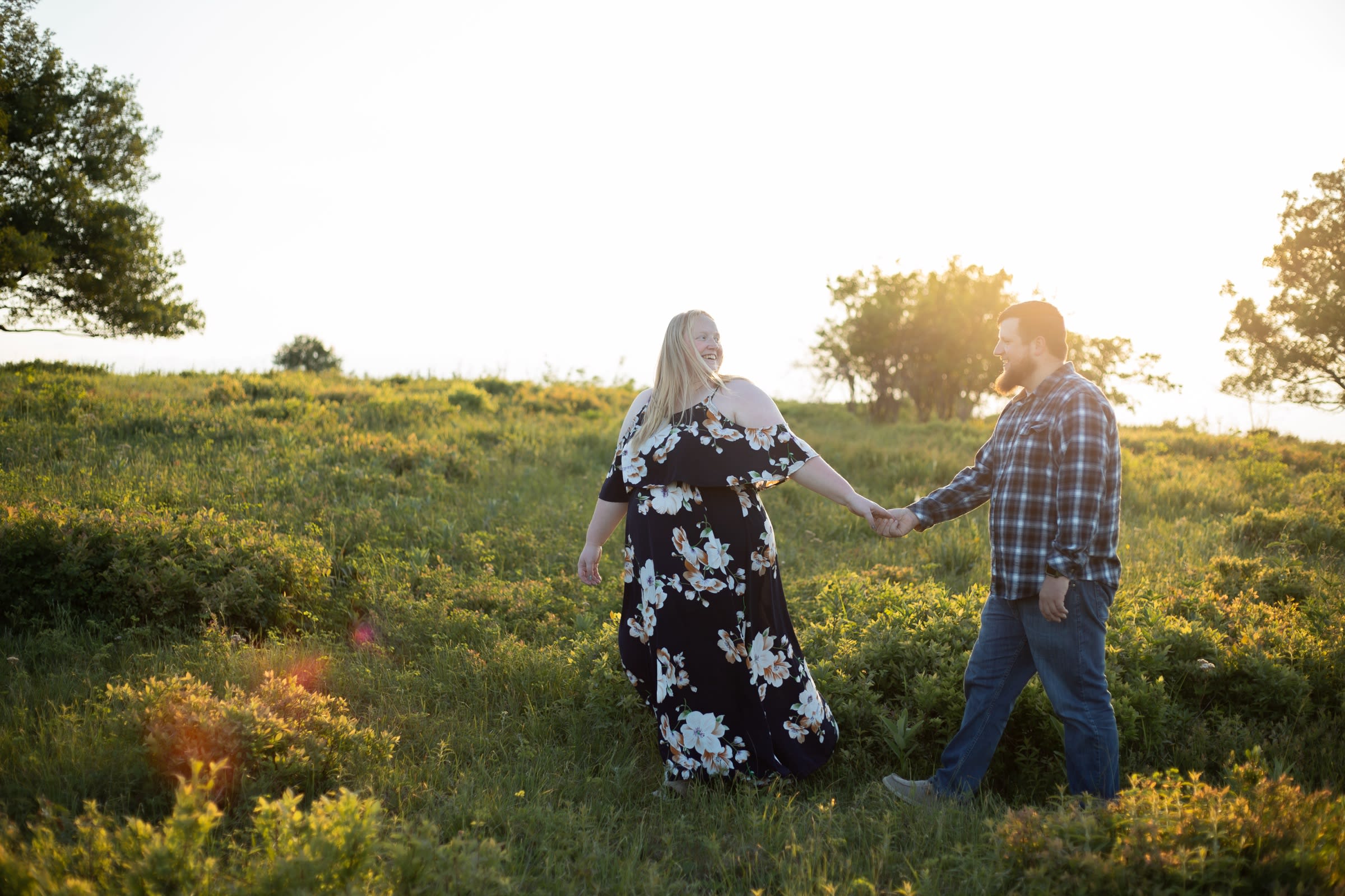 Couple holding hands and walking through a summer wildflower meadow in golden evening light in Shenandoah National Park