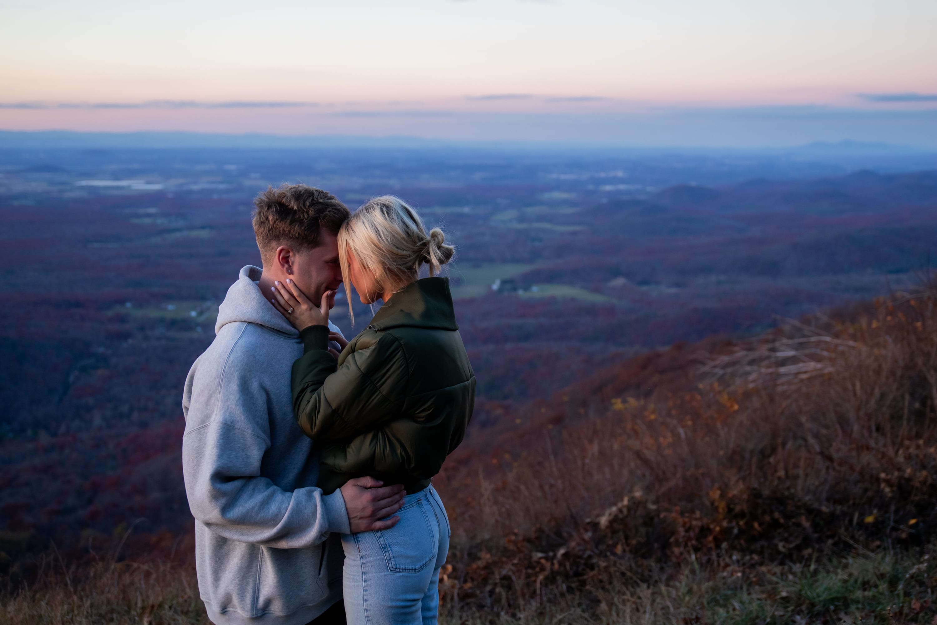 Couple at twilight with a purple and pink sunset fading over the mountains at Raven's Roost Overlook, Virginia
