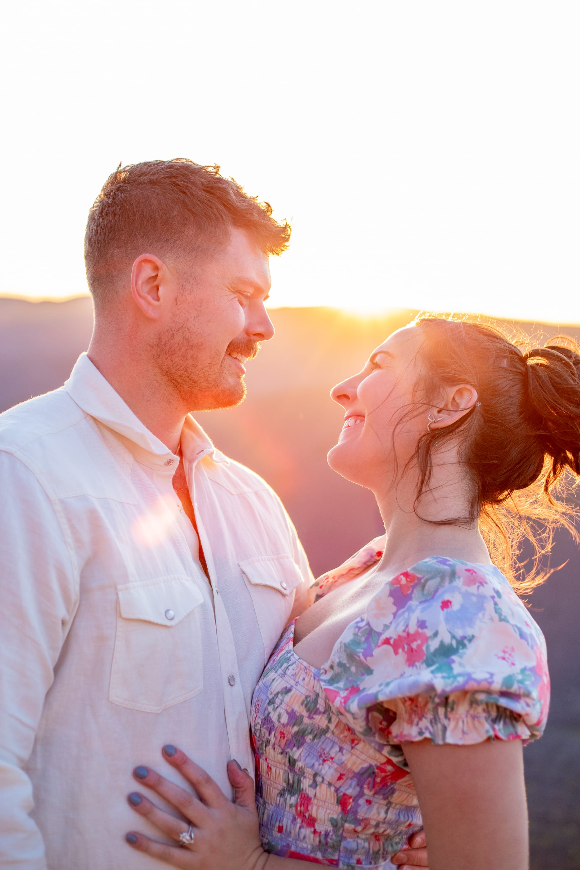Golden and pink sunset over the mountaintop behind a couple at Raven's Roost Overlook on the Blue Ridge Parkway