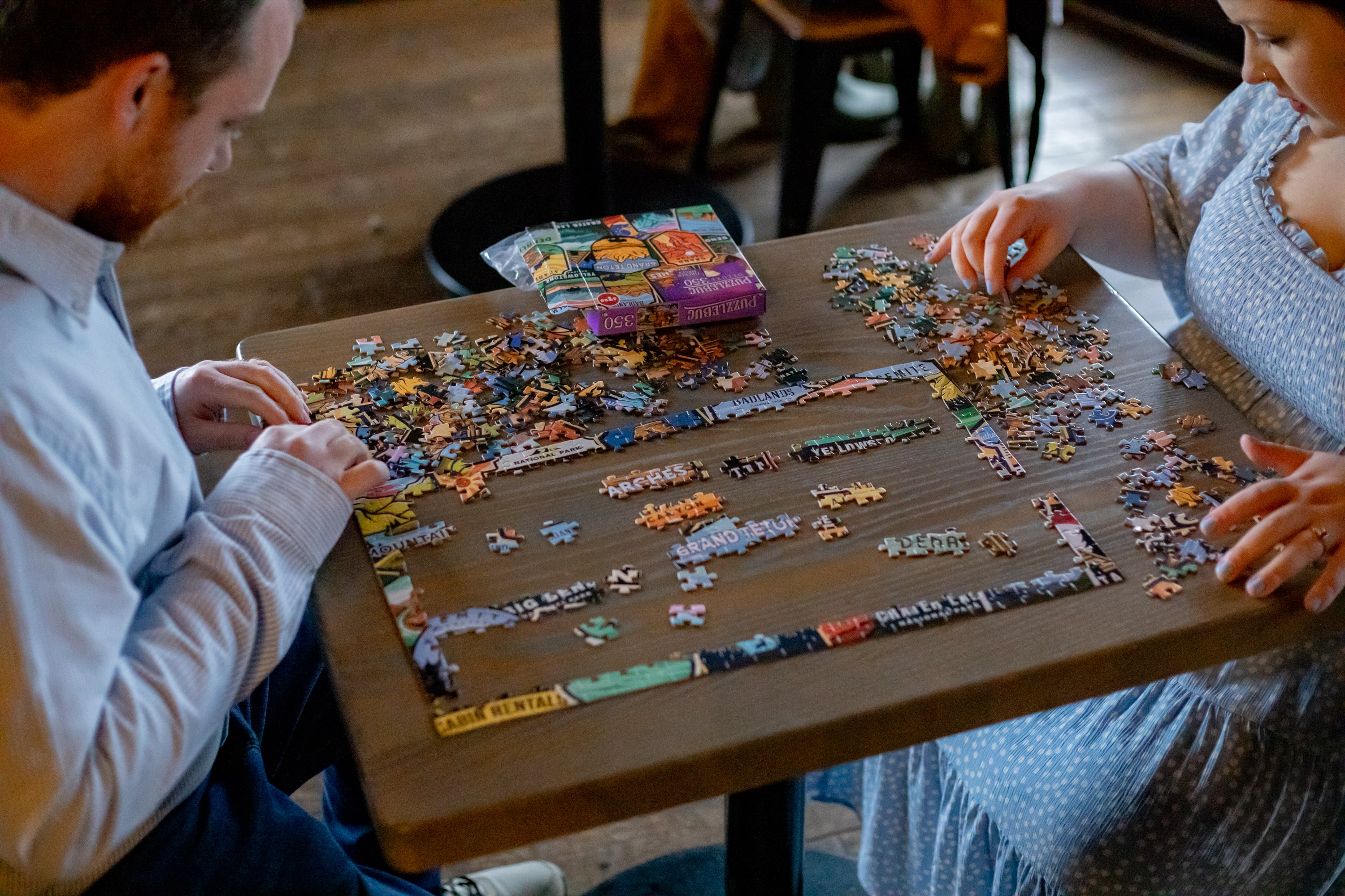 Couple doing a national parks puzzle together at a table inside the Big Meadows taproom