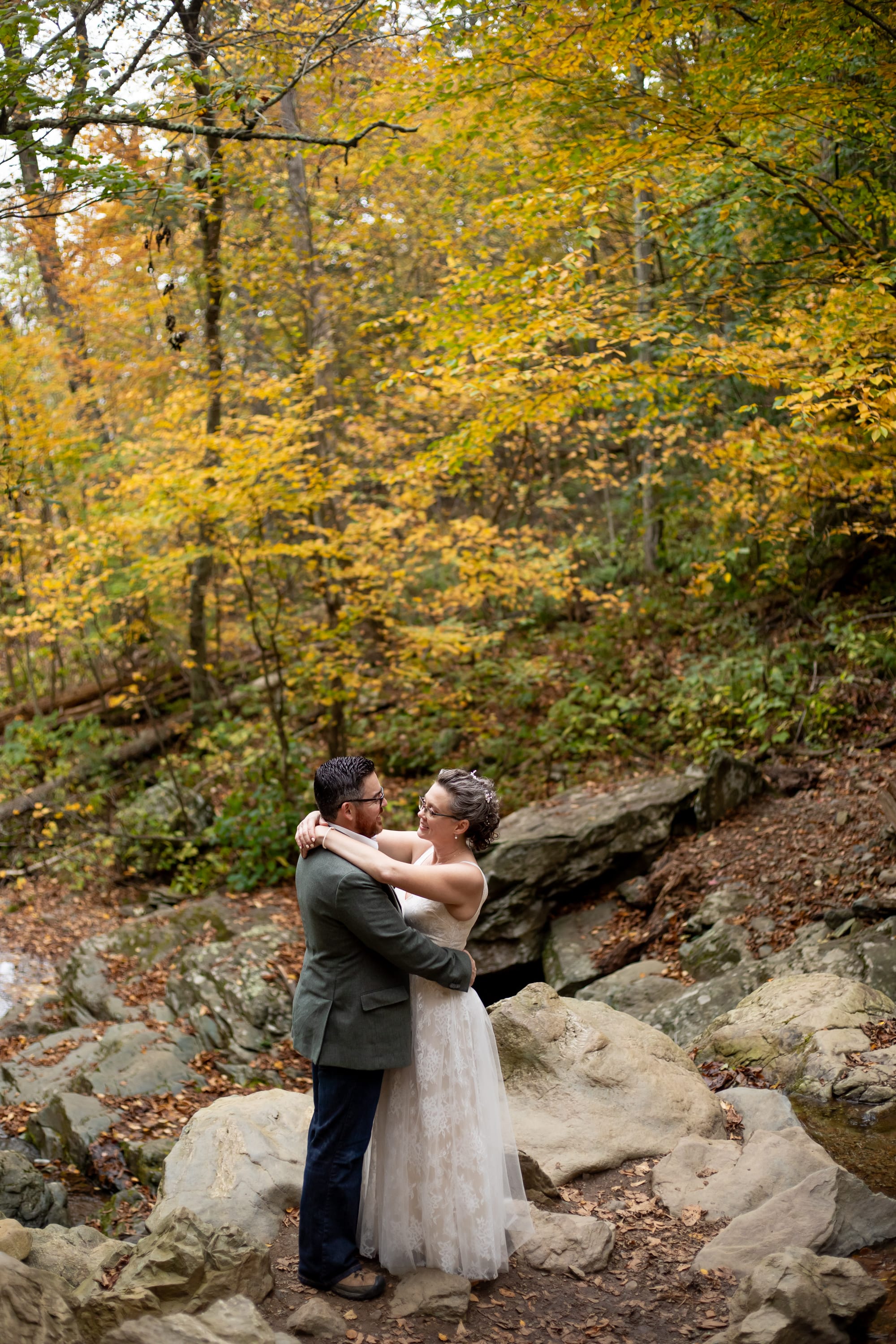 Couple eloping at the bottom of Dark Hollow Falls under peak fall foliage in Shenandoah National Park, Virginia