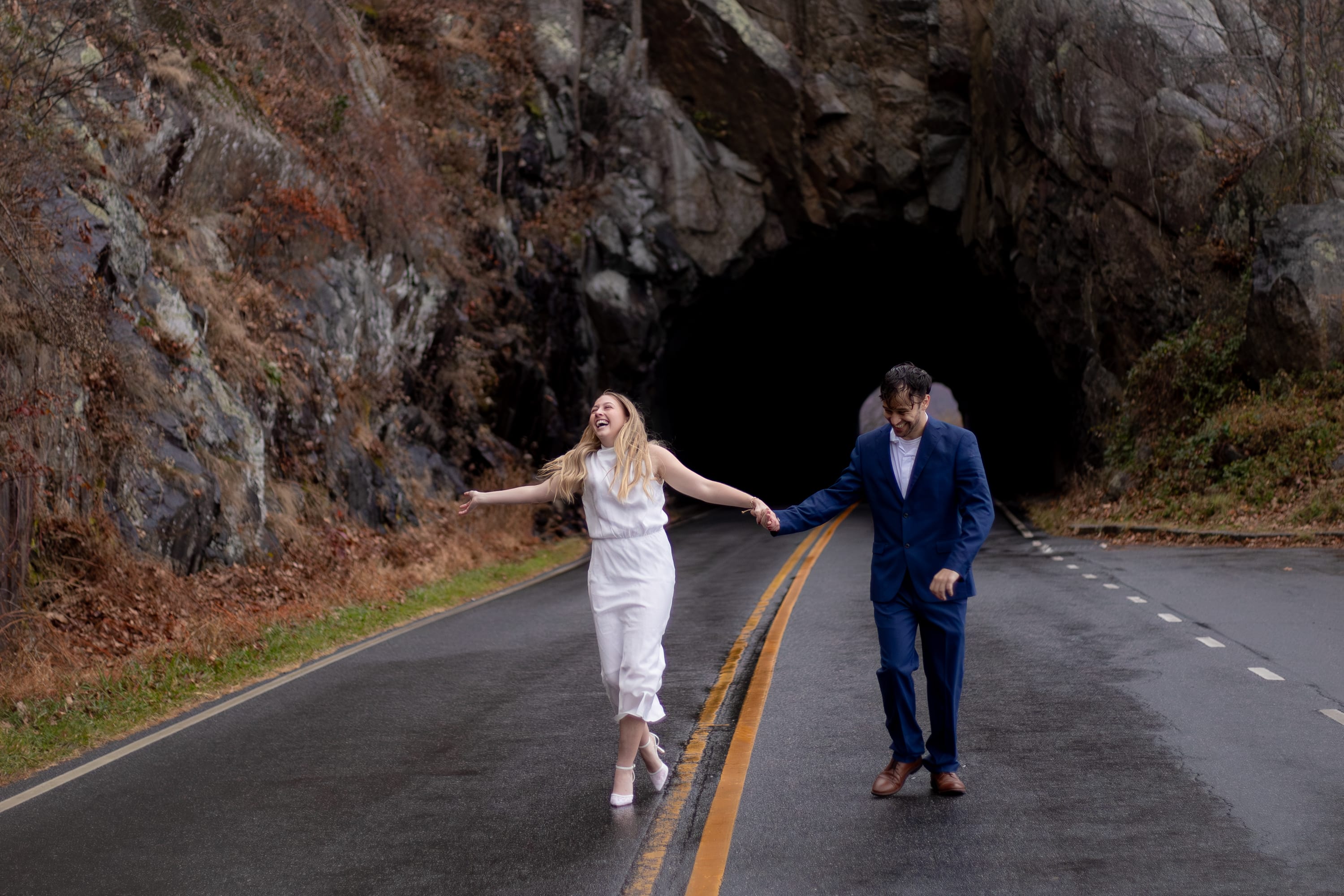 couple running together along Skyline Drive in the rain near Marys Rock in Shenandoah National Park during their elopement