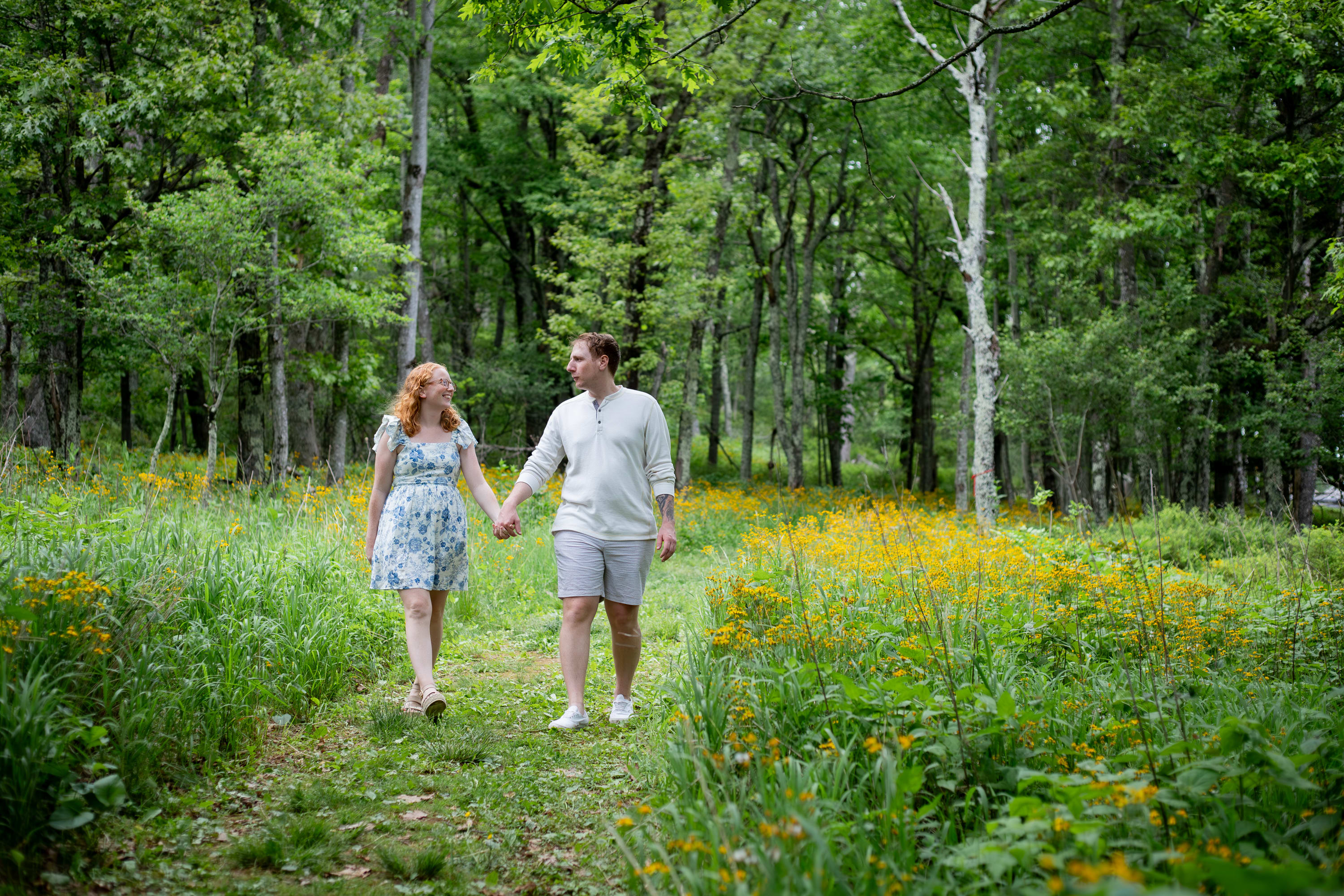 Couple walking hand in hand through lush forest with spring wildflowers carpeting the ground at Big Meadows, Shenandoah National Park