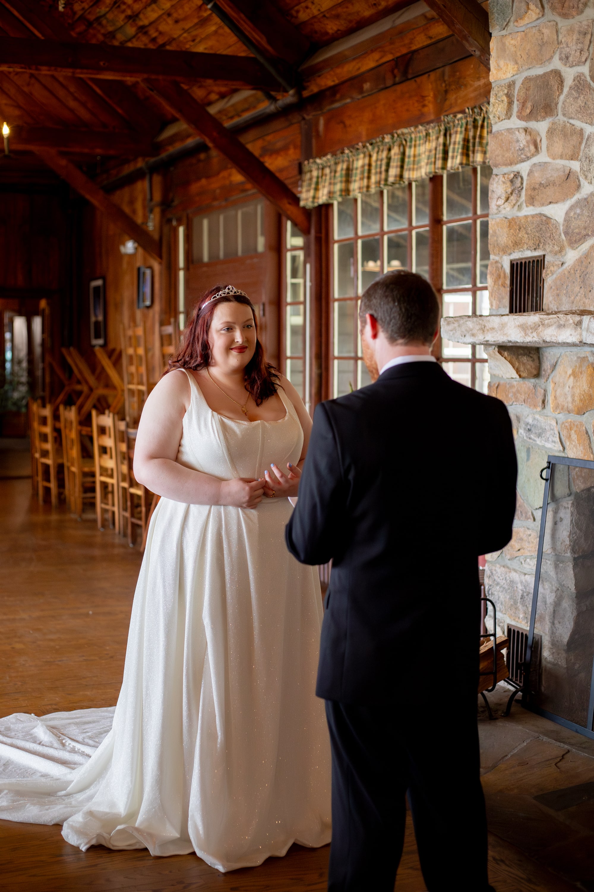 Bride and groom sharing a first look moment inside the Great Room at Big Meadows Lodge, stone fireplace and wooden beams behind them