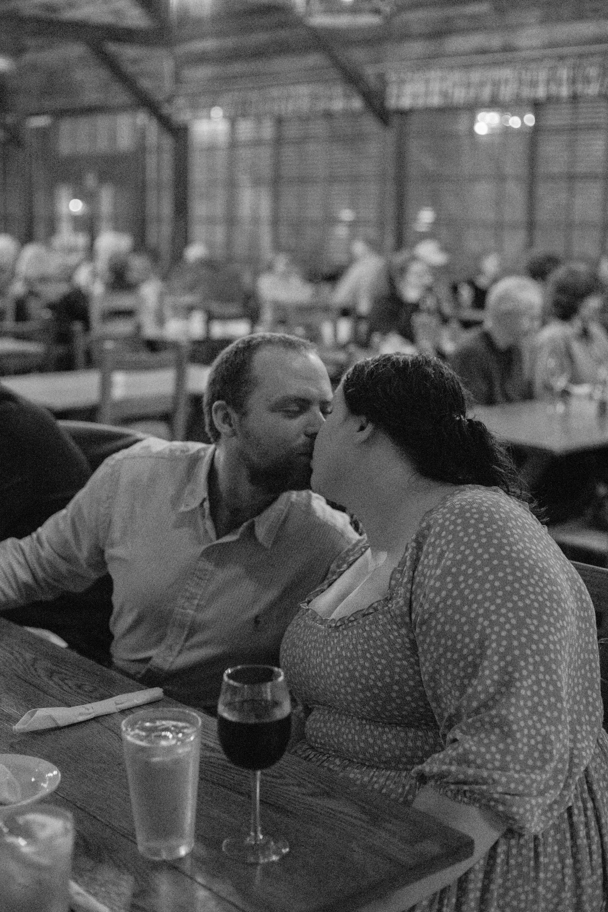 Couple sharing a quiet kiss at the bar inside Big Meadows Lodge, captured in black and white