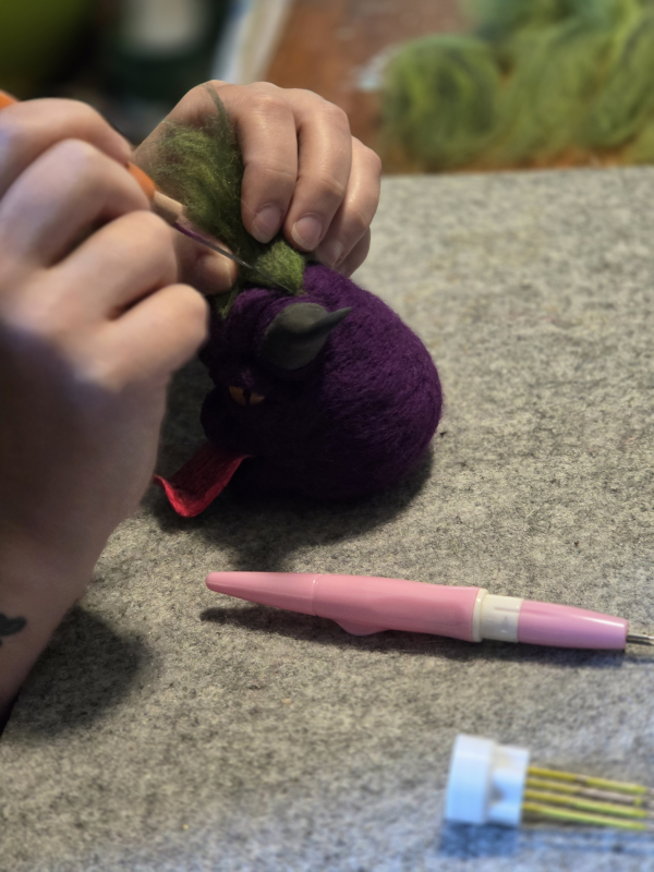 An artist working on the fine details of a felted piece