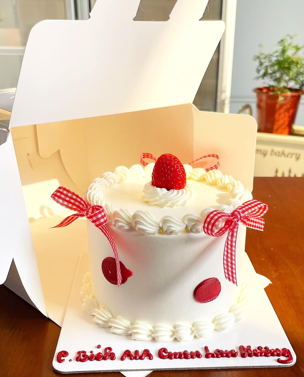 Bánh kem trắng nơ ca rô đỏ dâu tây
