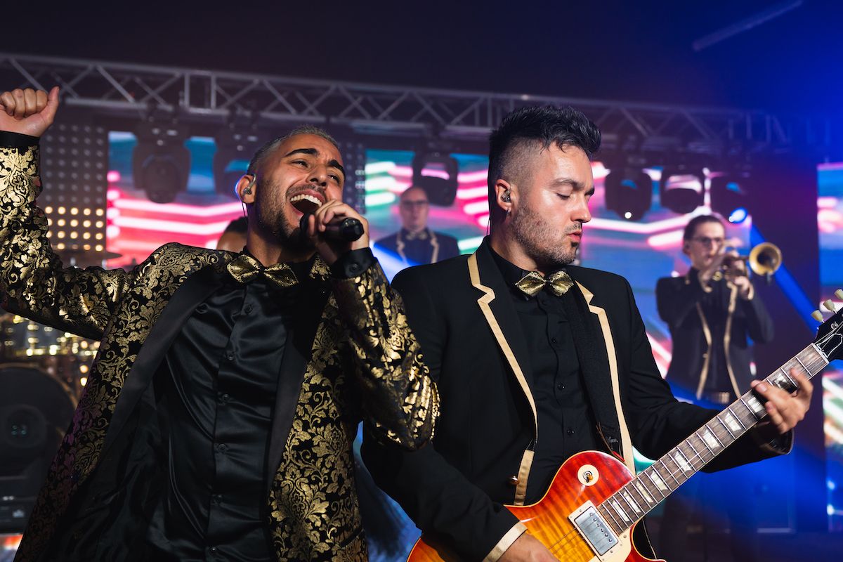 Jam Hot singer & guitarist on stage wearing dapper gold