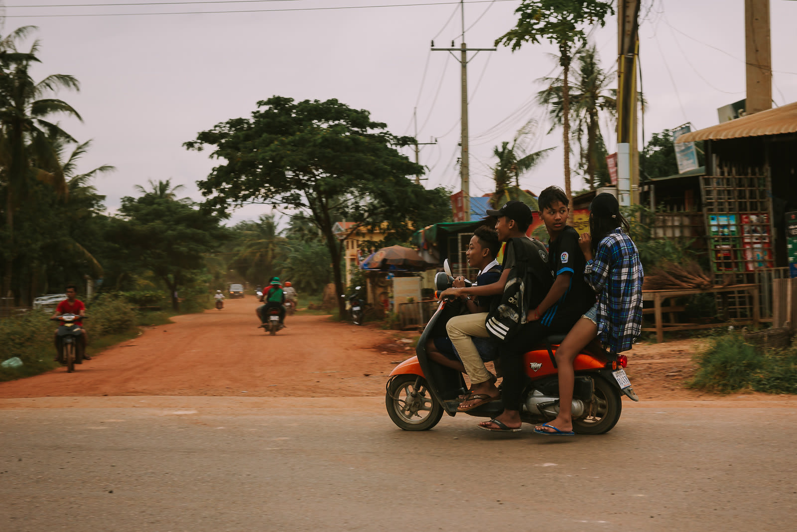 Four kids on one moped on a dirt road