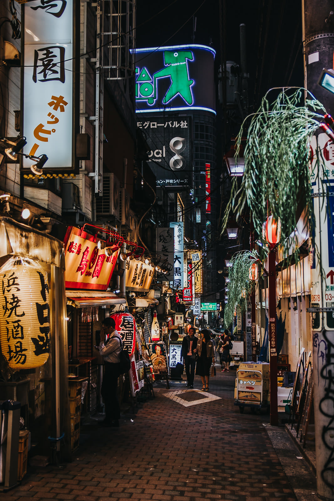 Small Tokyo street at night lit up with lights