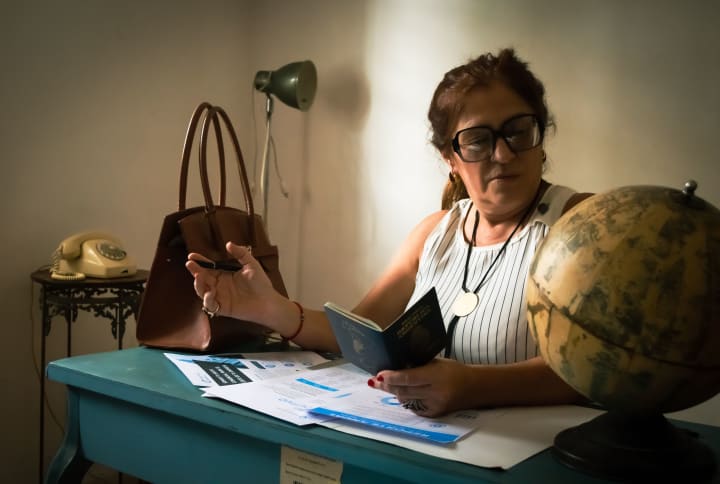 Traveller reviewing a passport and planning documents at a desk beside a globe.