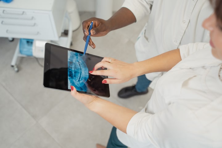 Dentist reviewing dental X-ray information on a tablet with a patient.