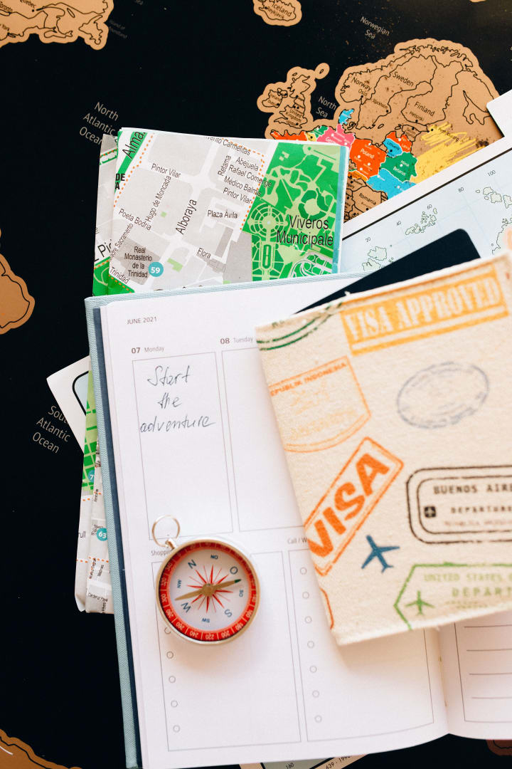 Travel notebook, compass and map arranged for international journey planning