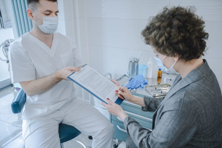 Patient and healthcare professional reviewing documents together in a clinic.