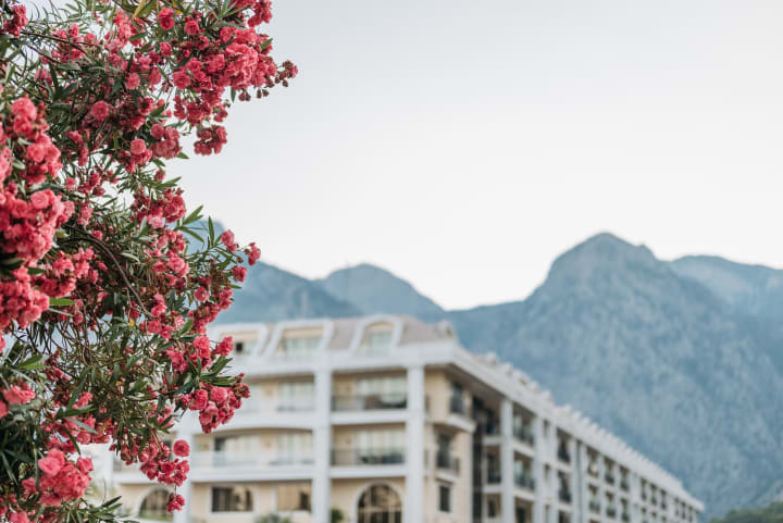 Flowering accommodation grounds with a mountain backdrop in the Antalya region.