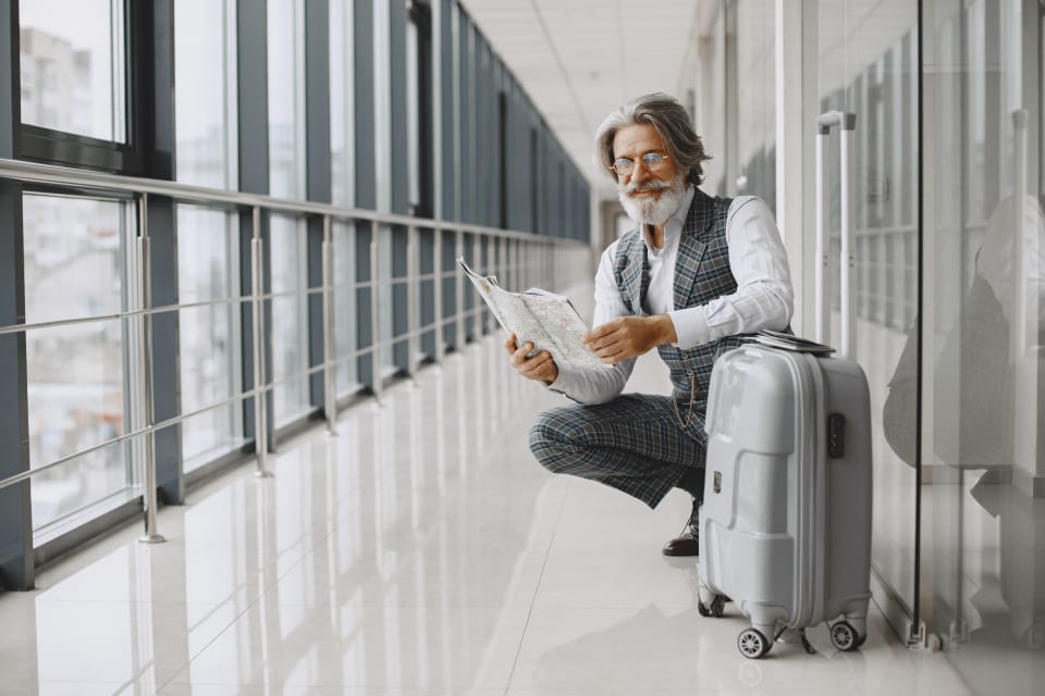 Older traveller reviewing a map beside luggage while planning an international journey.
