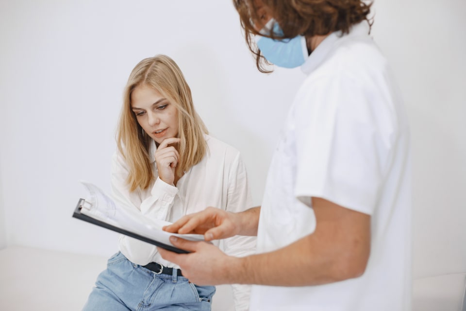 Doctor and patient reviewing information on a clipboard during a clinic consultation.