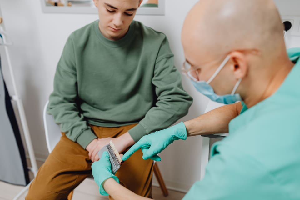 A dentist in a mask shows dental options to a young patient in a clinic.