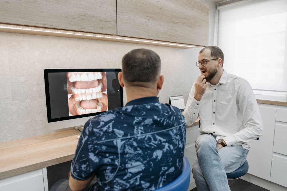 Dentist discussing dental X-ray results with a patient during a consultation in a modern clinic.