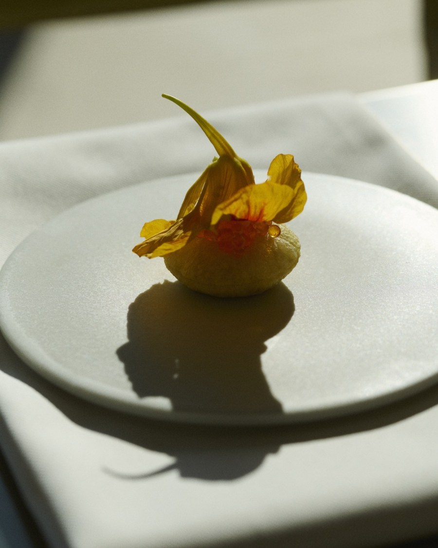 Lunette restaurant interior, warm lighting and handblown glassware within brutalist concrete