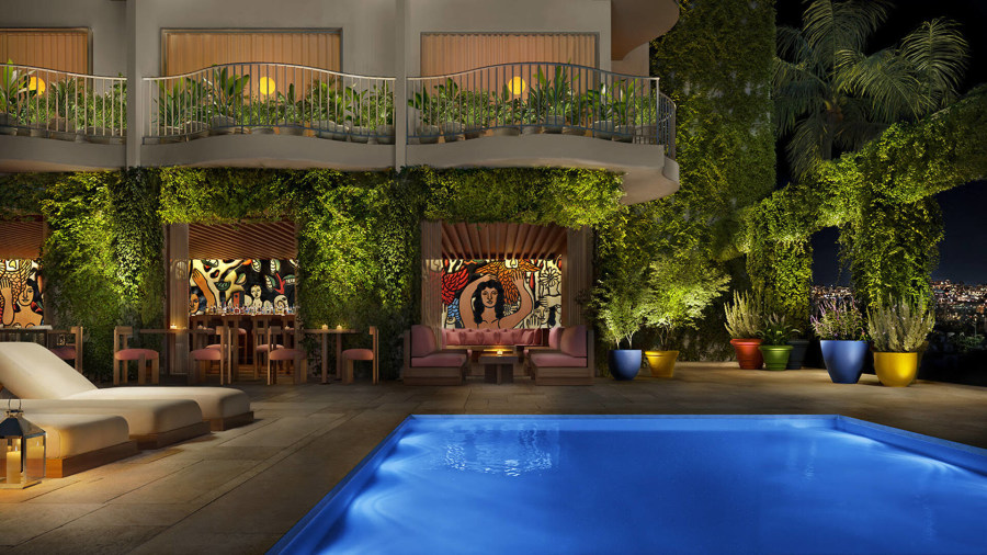 Public West Hollywood pool terrace at night with living wall, blue pool, coral lounge chairs and colourful murals