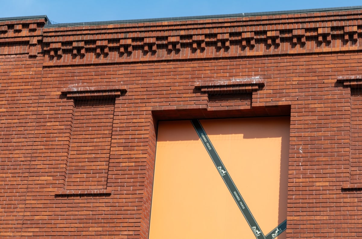 Brick detail with Hermès Paris branded ribbon strip and carriage motif on the building facade