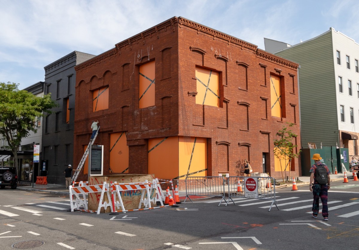 Hermès building corner under renovation with boarded windows and construction barriers
