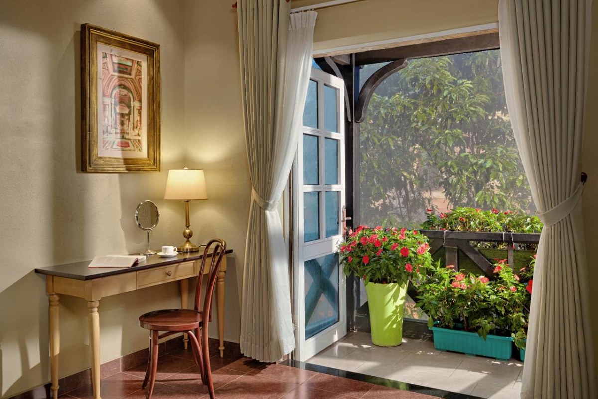 French Village cobblestone square with Gothic cathedral spires, flower beds, and vintage car at Mercure Bana Hills