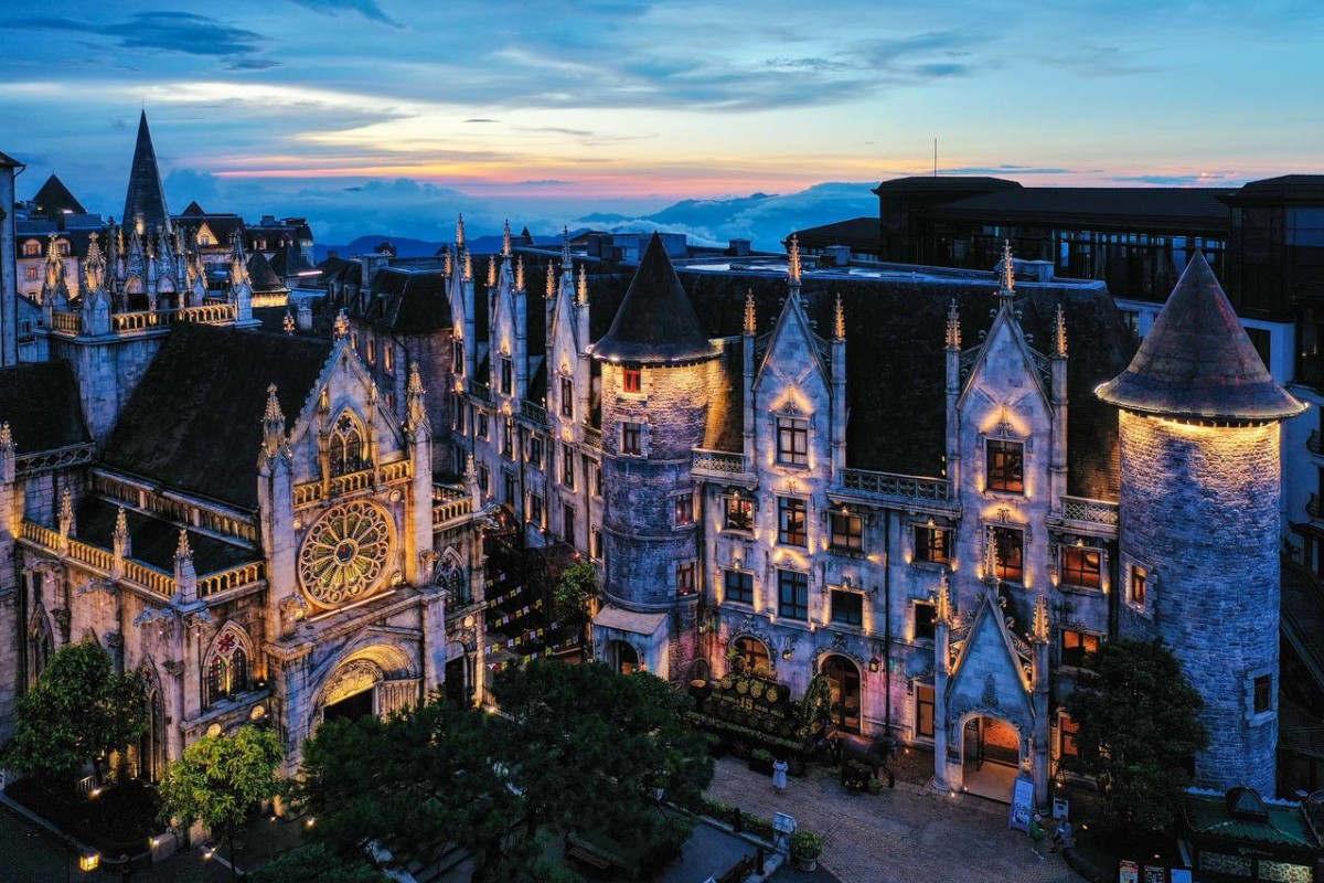 Aerial view of the French Village at sunset with illuminated spires and mountain backdrop