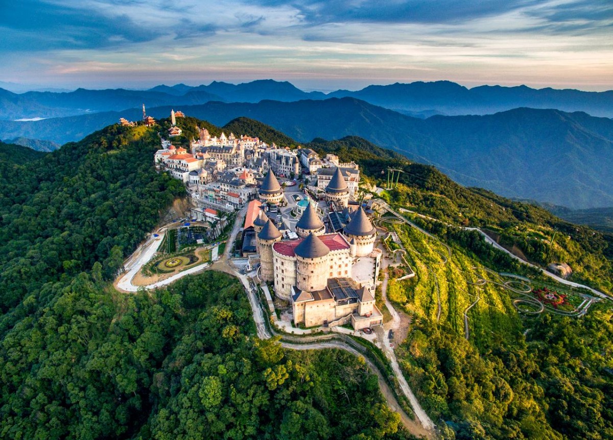 Gothic spires and stone facades illuminated at golden hour, Mercure French Village Bana Hills